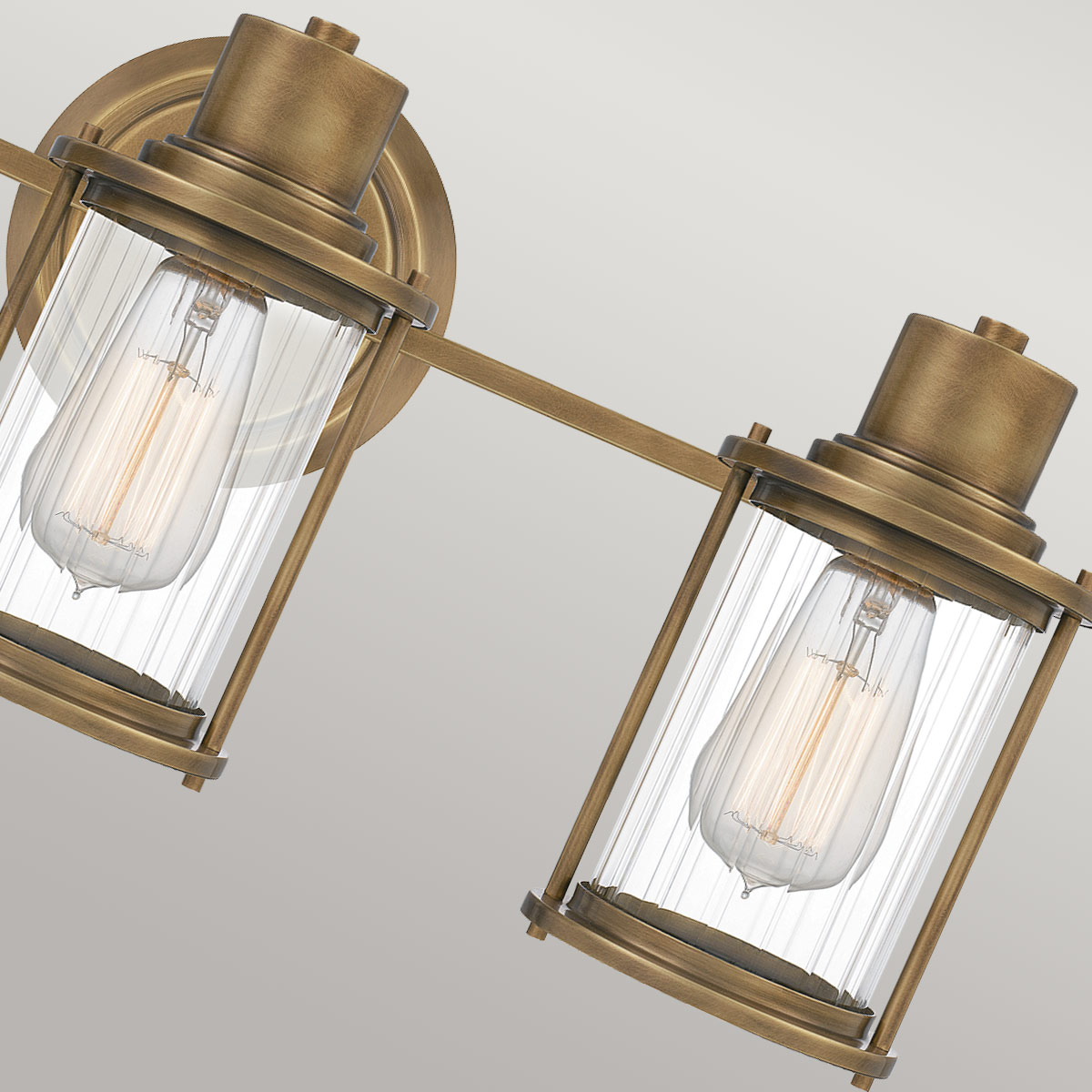 Riggs 56cm Latón crudo lámpara de baño De Elstead Lighting - La lámpara de pared Riggs, fabricada en cristal sin marco, combina un diseño industrial ligero con detalles elegantes como el cristal transparente acanalado.