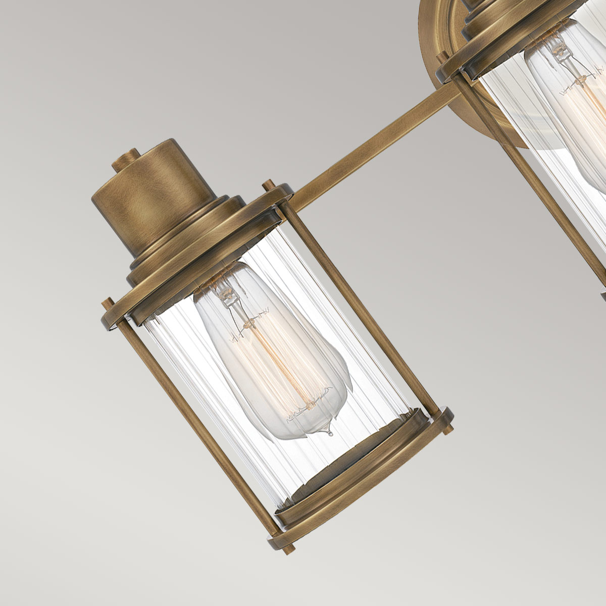 Riggs 56cm Latón crudo lámpara de baño De Elstead Lighting - La lámpara de pared Riggs, fabricada en cristal sin marco, combina un diseño industrial ligero con detalles elegantes como el cristal transparente acanalado.