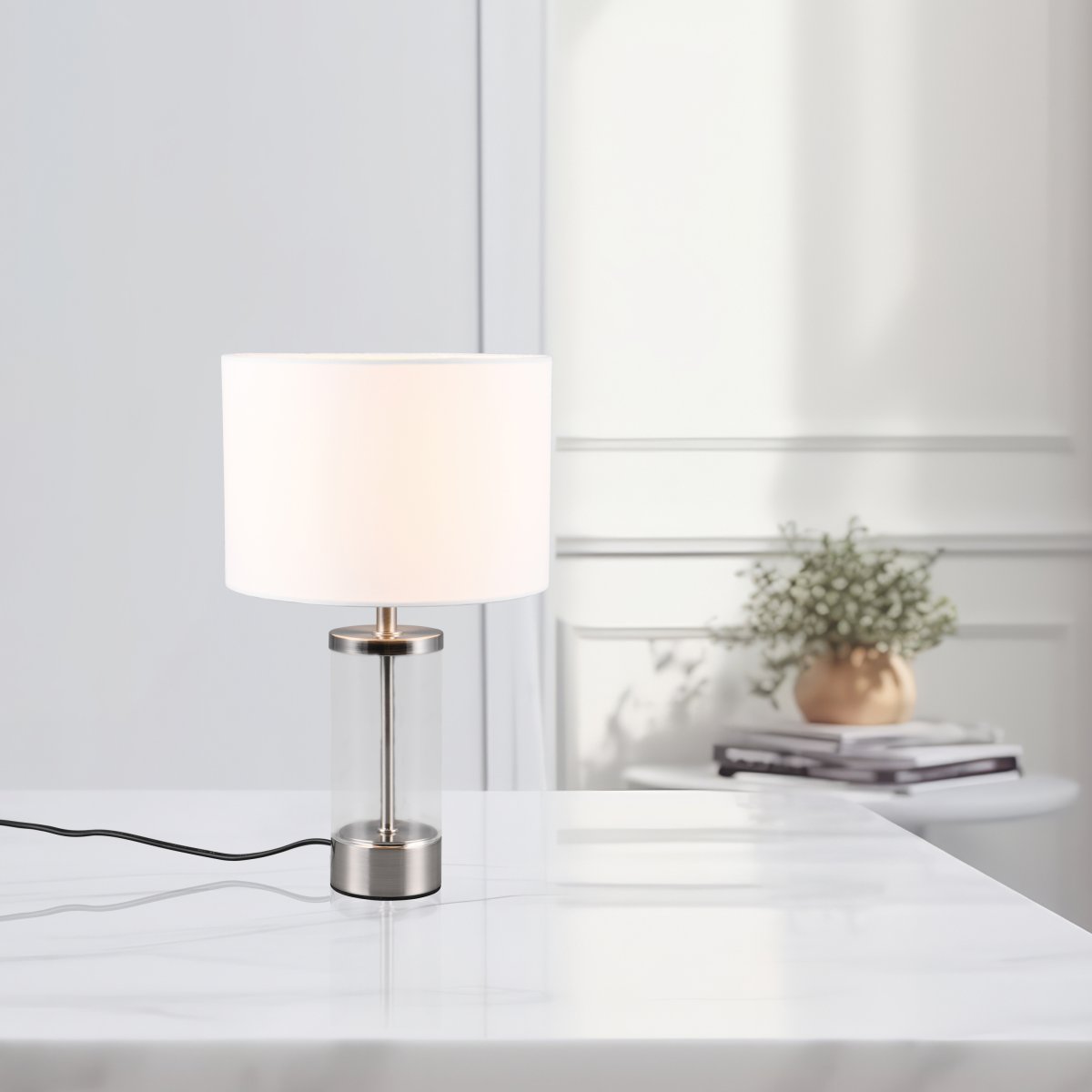 Grazia 34cm Blanco lámpara de mesa De Trio Lighting - La lámpara de mesa Grazia combina una elegante pantalla de tela con una elegante base cilíndrica de vidrio y metal, creando una impresión armoniosa y elegante.
