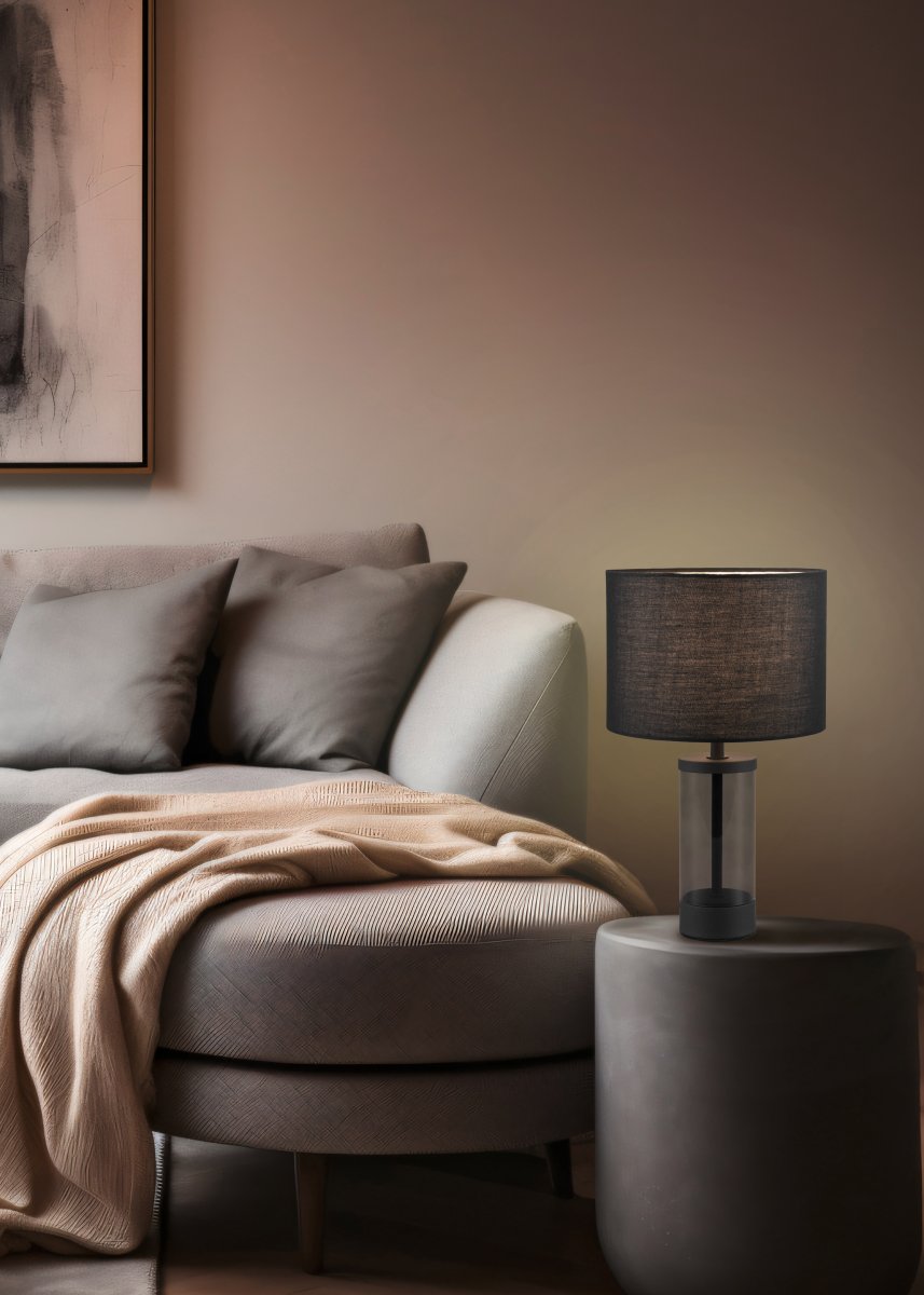 Grazia 34cm Negro lámpara de mesa De Trio Lighting - La lámpara de mesa Grazia combina una elegante pantalla de tela con una elegante base cilíndrica de vidrio y metal, creando una impresión armoniosa y elegante.