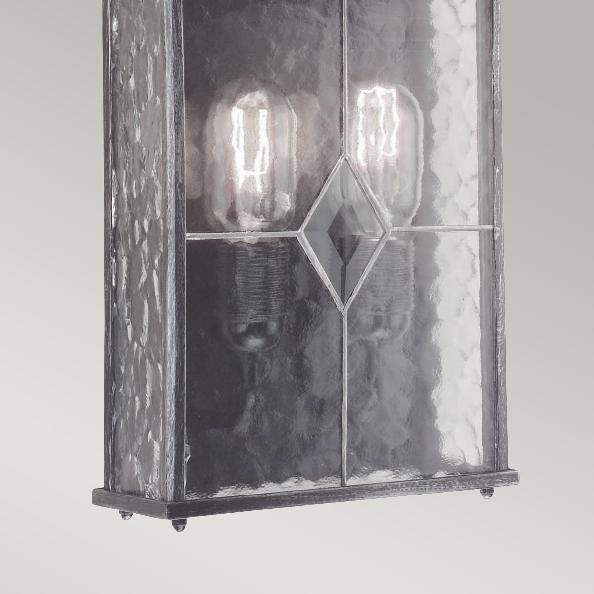 Wexford Plata lámpara de exterior De Elstead Lighting - Wexford es una lámpara de pared clásica para exteriores, fabricada en aluminio con un elegante acabado en plata oscura y paneles de vidrio decorativos con textura de vidrieras emplomadas.